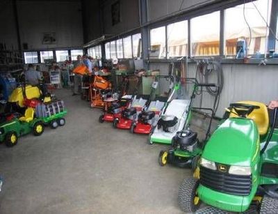 Ein Geschäft, in dem verschiedene Rasenmäher und andere Gartengeräte ausgestellt sind.