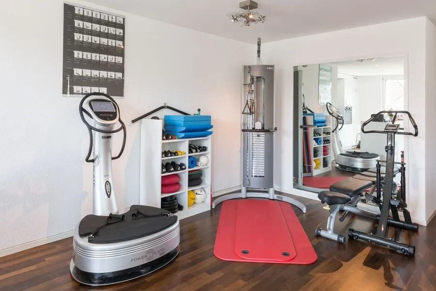 Ein Fitnessstudio mit einer roten Matte, einem Gerät und einem Spiegel.