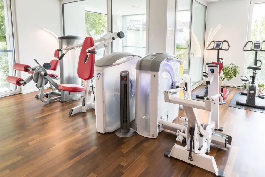 Eine Physiotherapiepraxis mit vielen Trainingsgeräten und Holzboden.