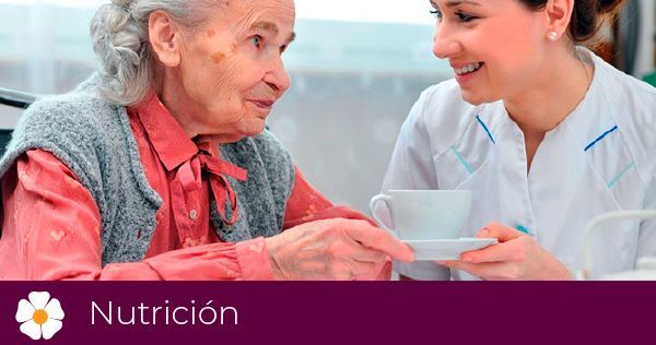 Una enfermera le está dando una taza de café a una anciana.