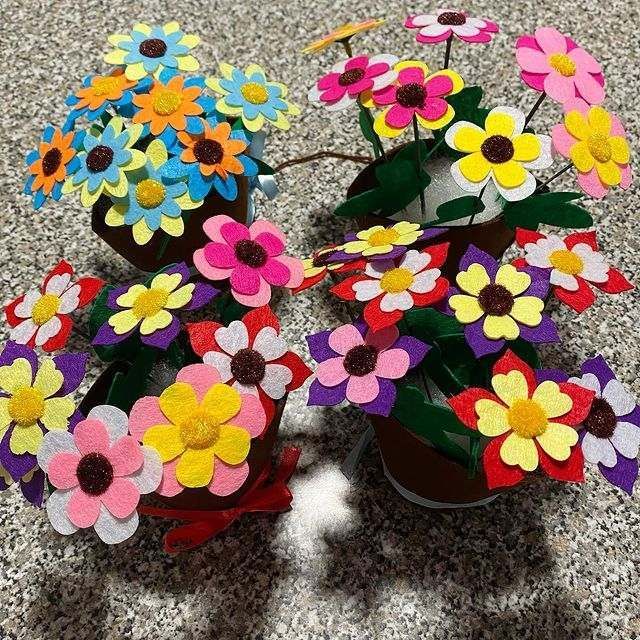 Un ramo de flores de fieltro en macetas en el suelo.