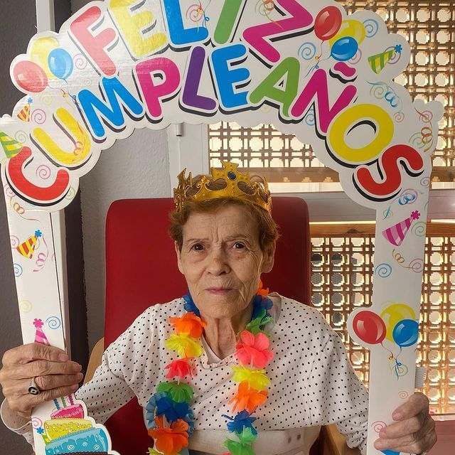Una mujer sosteniendo un cartel que dice feliz cumpleaños