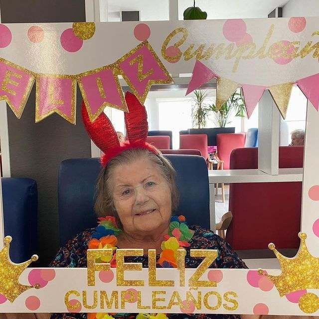 Una mujer sosteniendo un cartel que dice feliz cumpleaños
