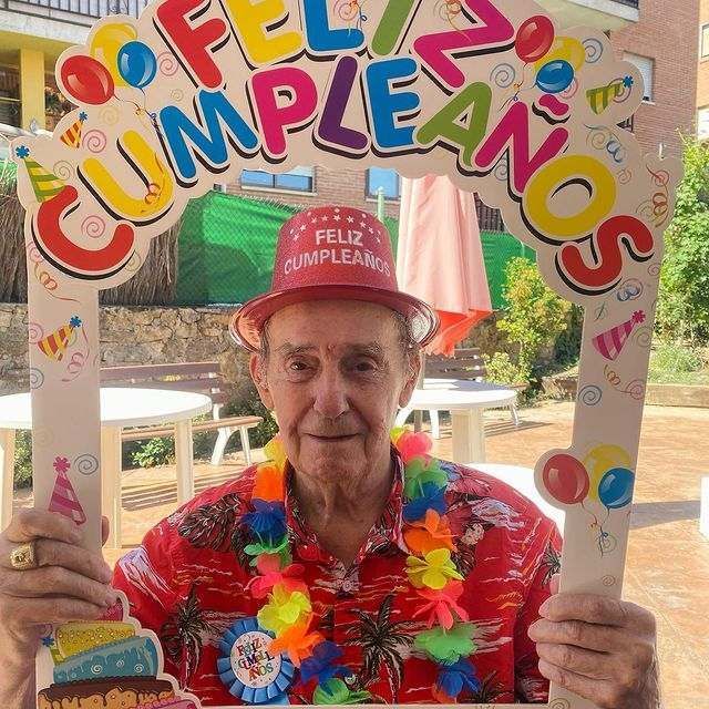 Un hombre mayor sostiene un cartel que dice feliz cumpleaños
