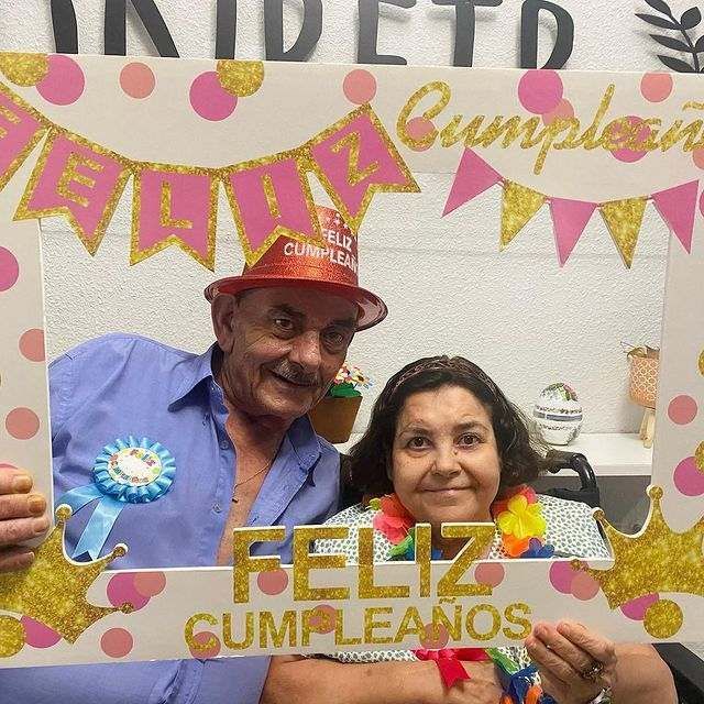 Un hombre y una mujer posan para una foto con un marco que dice Feliz Cumpleaños.