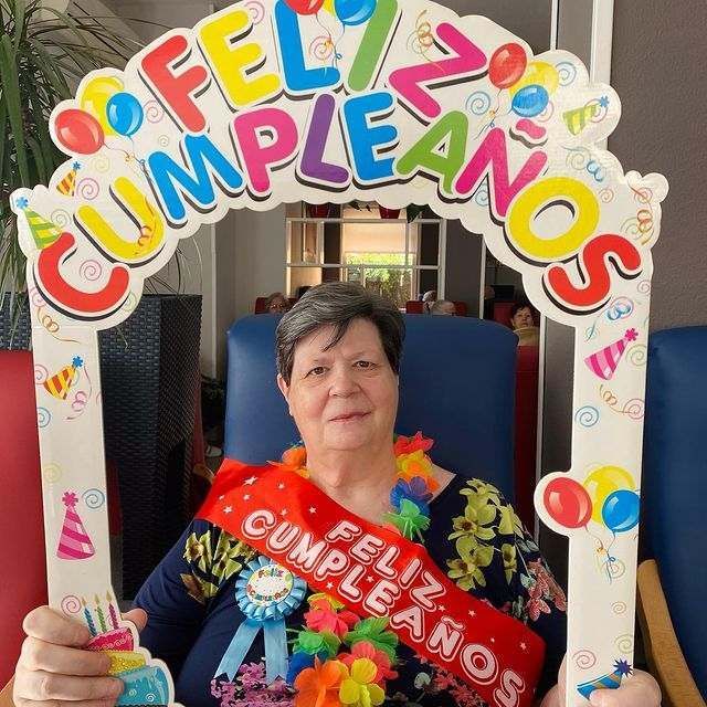 Una mujer sosteniendo un cartel que dice feliz cumpleaños