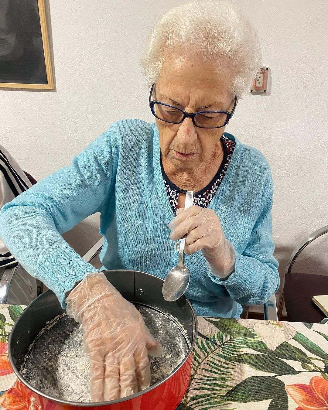 Una mujer mayor está mezclando algo en una olla con una cuchara.