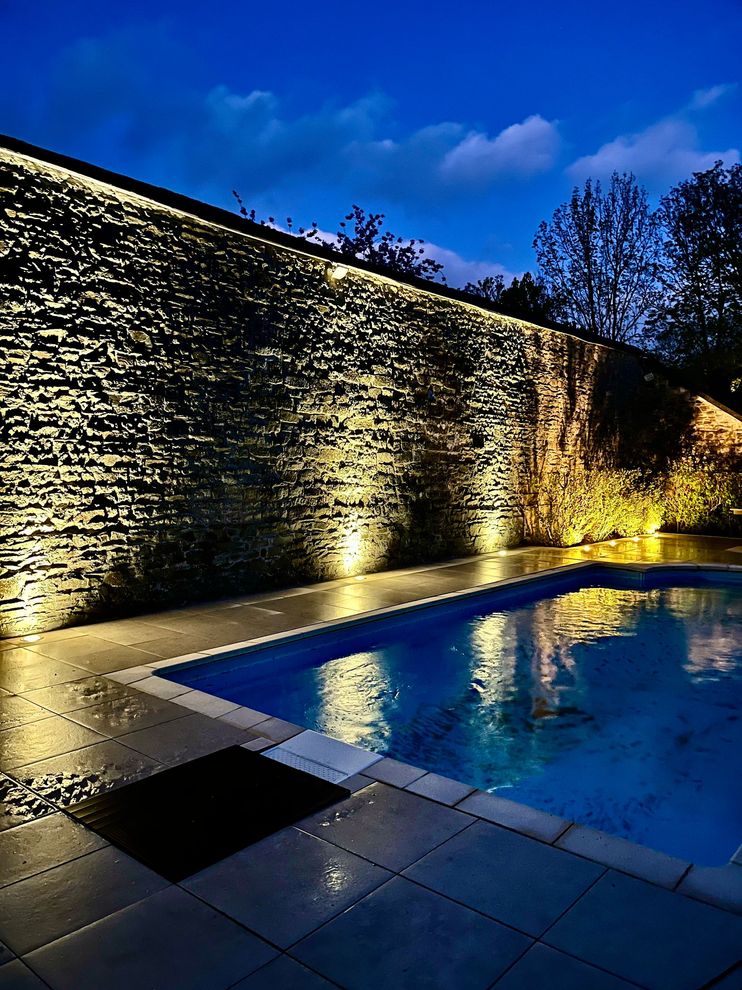 Piscine et mur en pierre vus de nuit