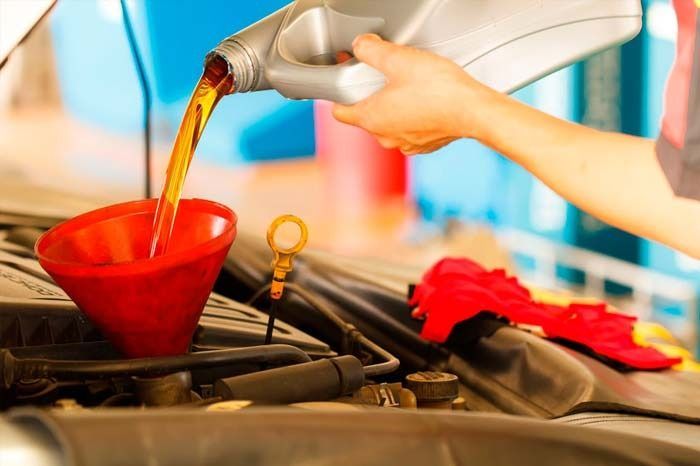 Una persona está vertiendo aceite en un automóvil a través de un embudo.