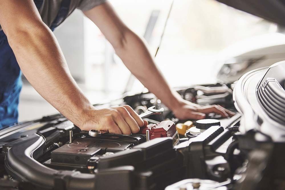 Un hombre está trabajando en el motor de un coche.