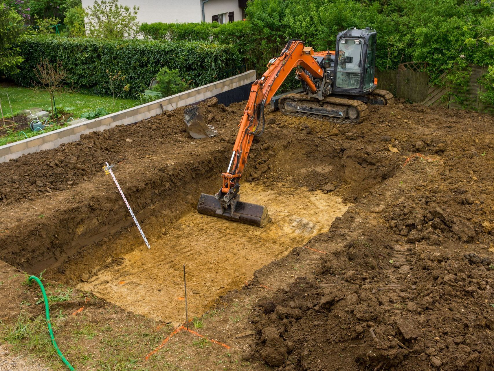 Une pelleteuse qui est en train de creuser le trou pour la piscine.