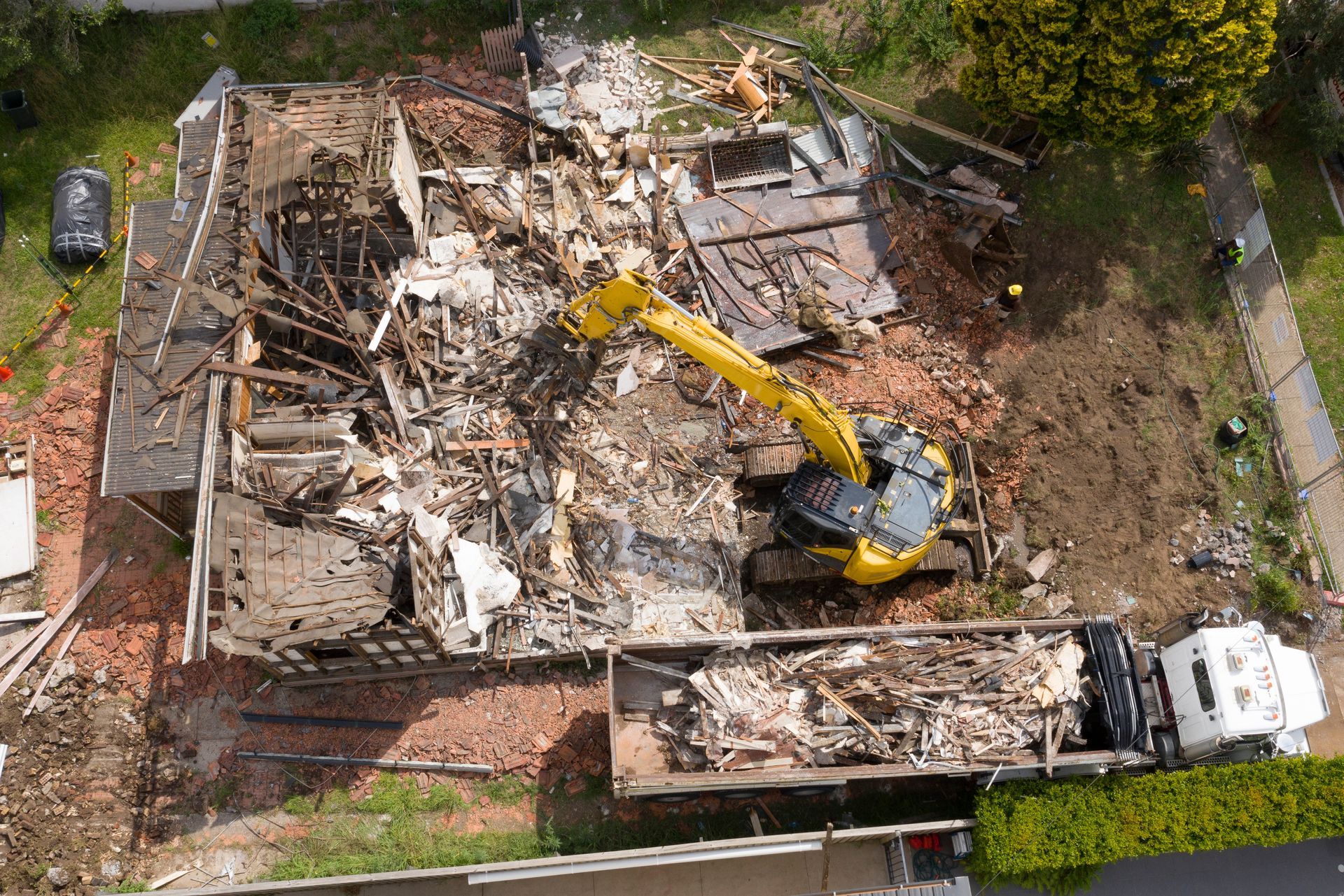 Vue aérienne sur un engin de chantier qui est en train d'enlever les débris d'une construction.