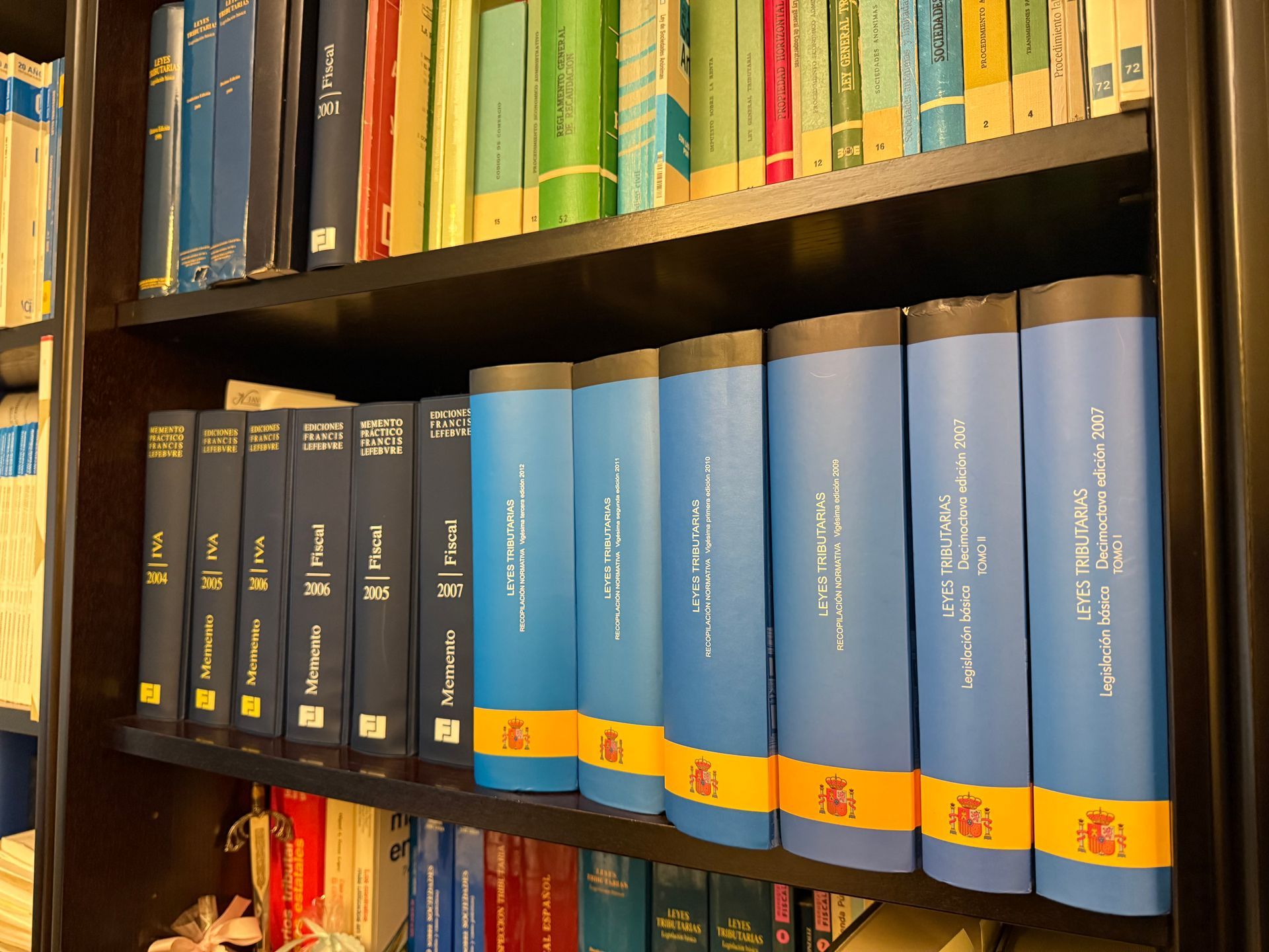 Estanterías llenas de libros encuadernados en azul y negro en una biblioteca o área de almacenamiento de oficina.