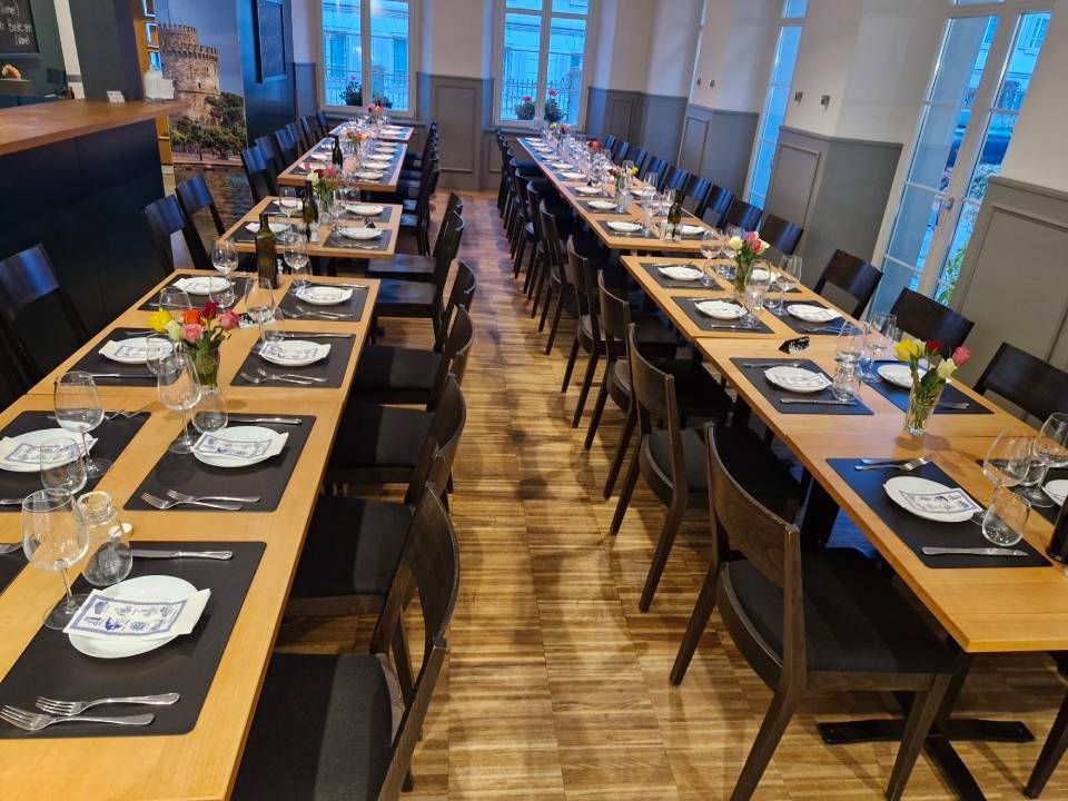 Für eine Mahlzeit gedeckte Restauranttische. Lange Holztische mit Gedecken, Stühlen und Blumen.