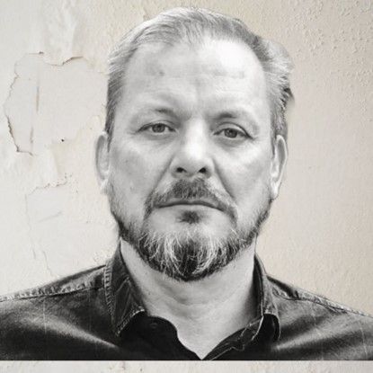 Un hombre con barba y bigote lleva una camisa negra.