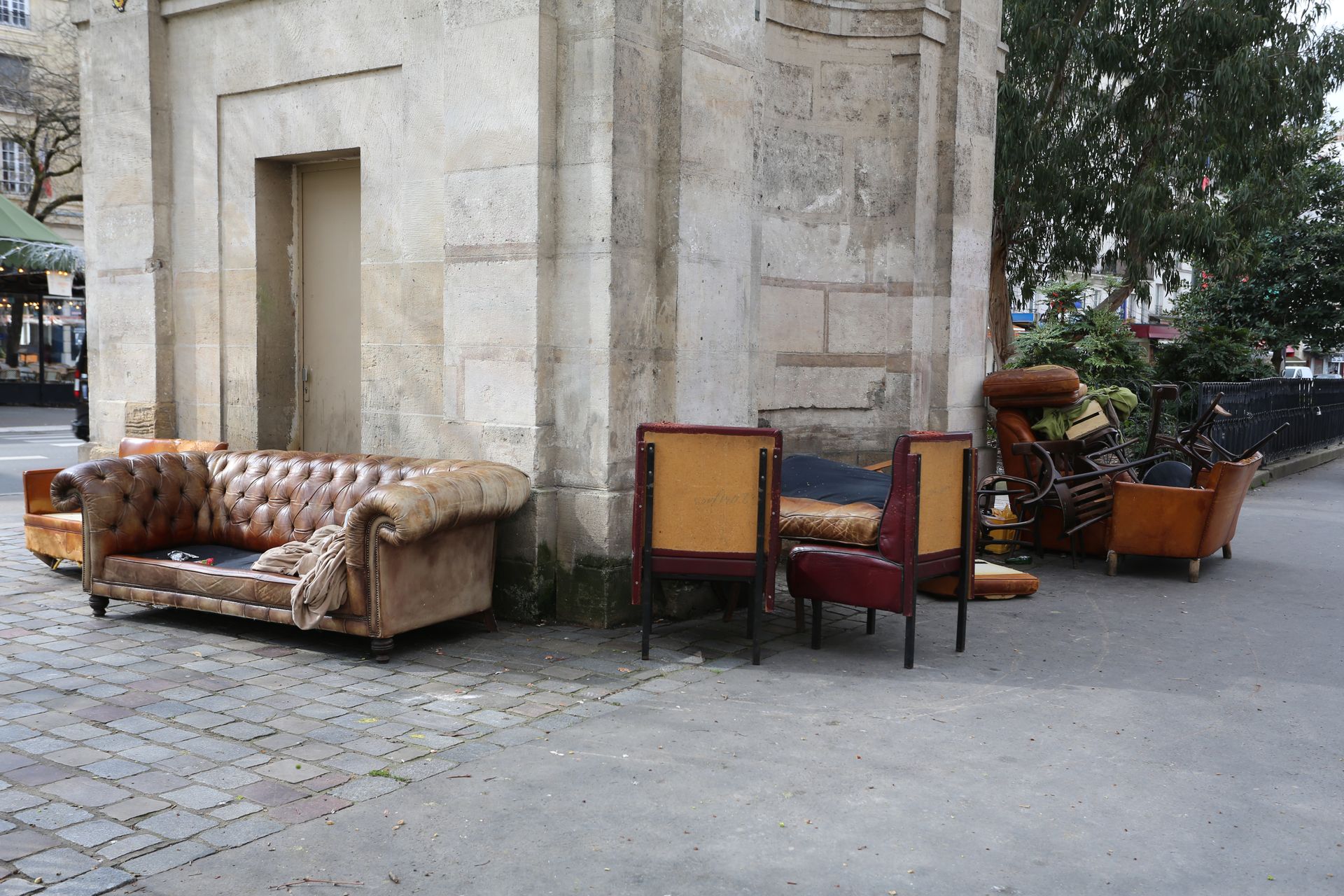 Des canapés et des chaises disposés autour d'un bâtiment en pierre sur une place publique extérieure.