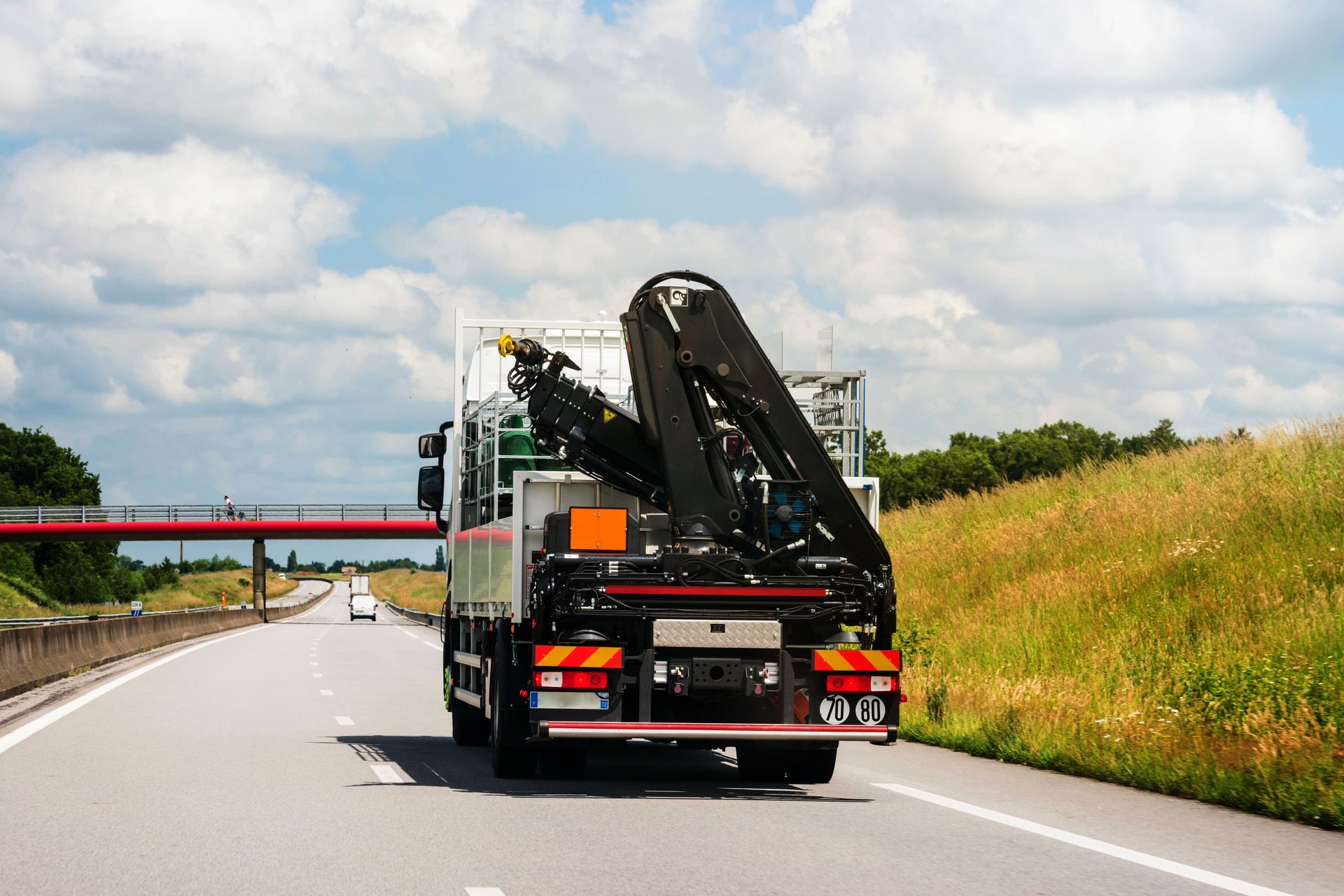Une dépanneuse transporte une voiture sur une autoroute, le long d'un talus herbeux, sous un ciel nuageux.