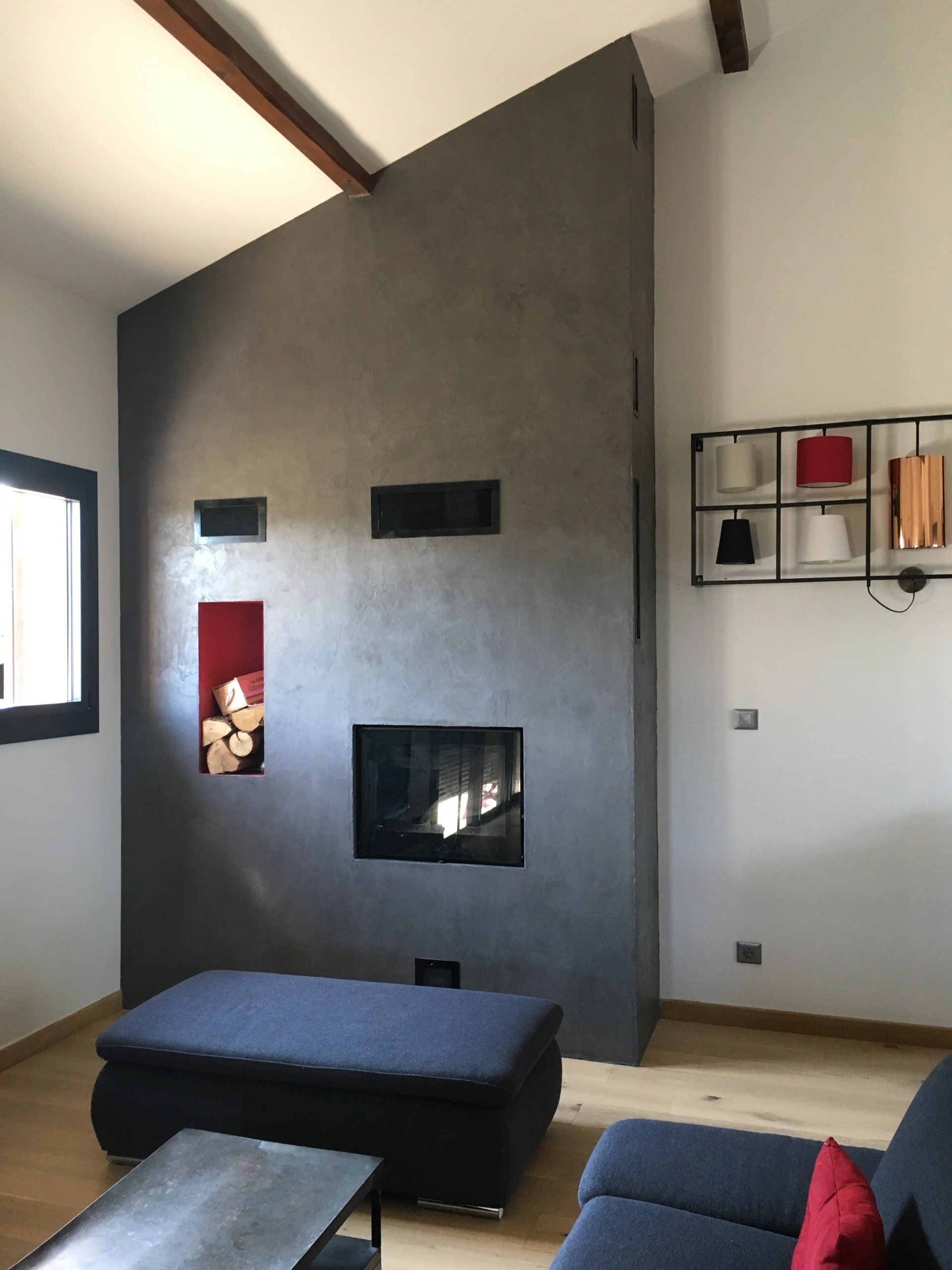 Cheminée encastrée dans un mur en stuc gris