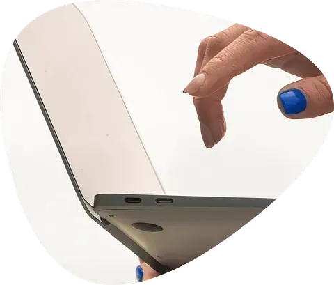 La mano de una mujer con uñas azules sostiene una computadora portátil.