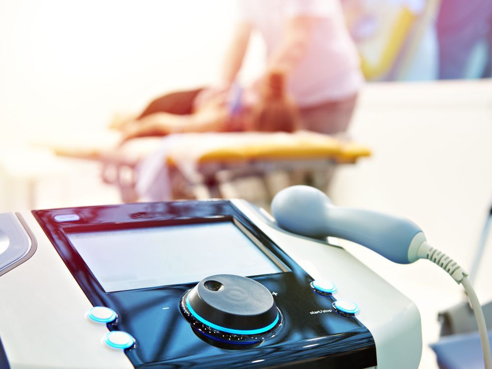 Una persona está recibiendo un masaje con una máquina al fondo.