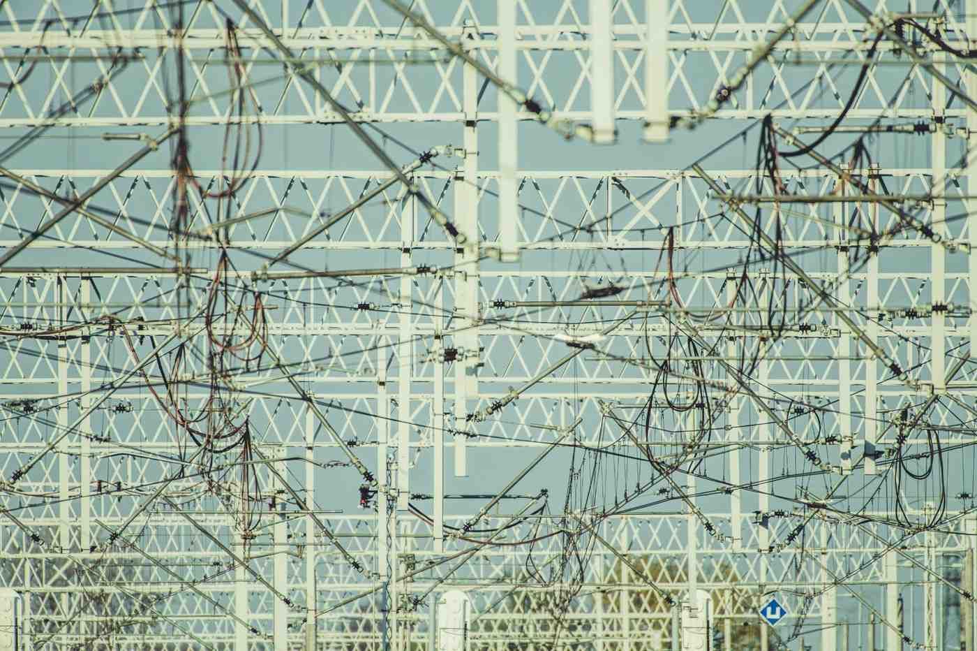 Estructura de metal blanco con cables enredados contra un cielo azul claro.