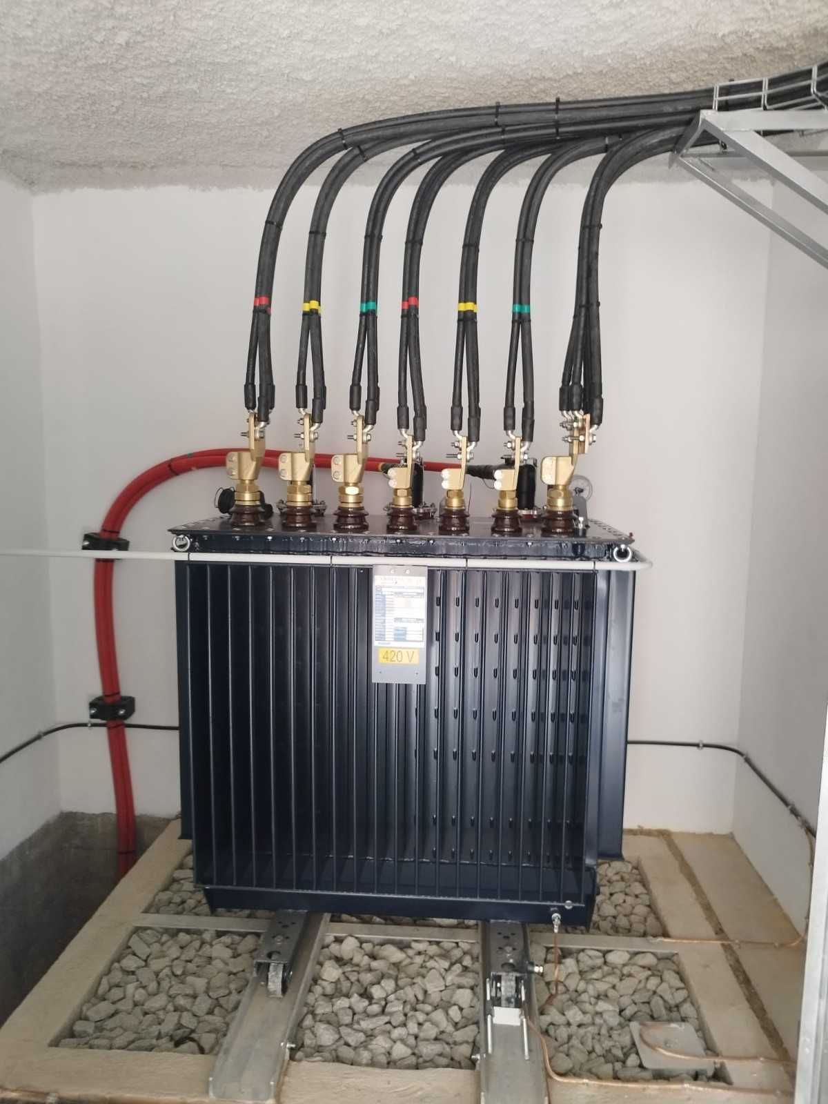 Manos con guantes amarillos examinan el panel de control eléctrico. Luces rojas y verdes encendidas.