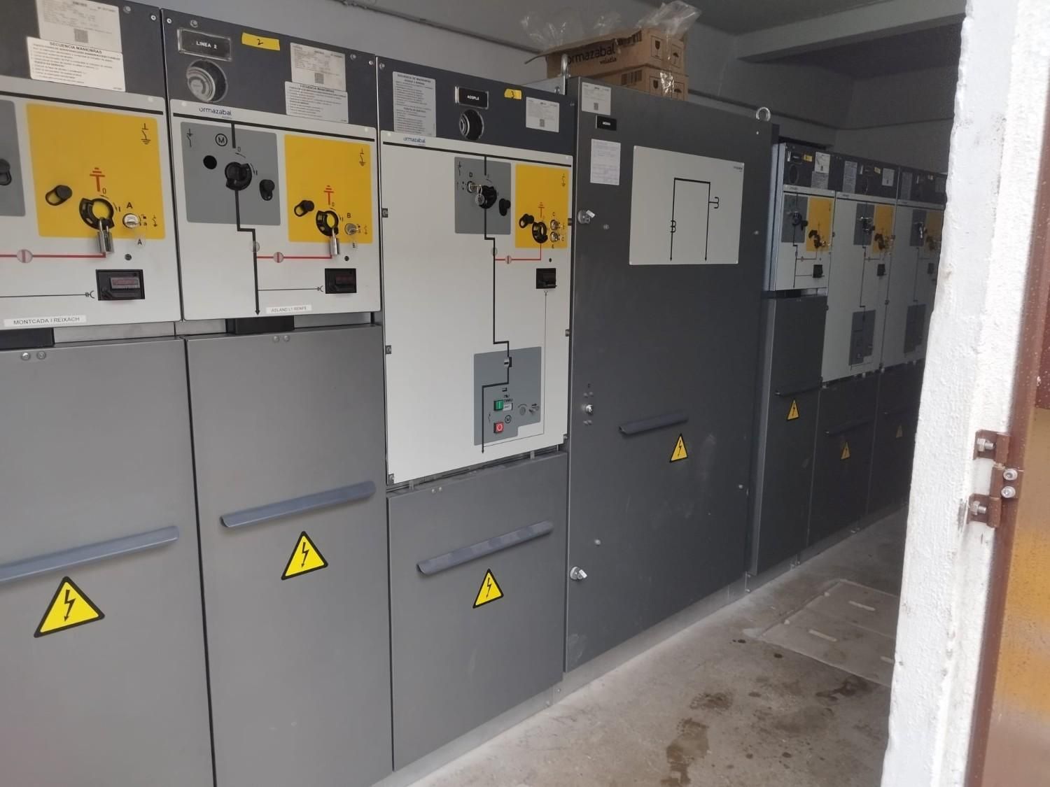 Subestación eléctrica con estructura metálica, aisladores y cableado frente a un cielo nublado.