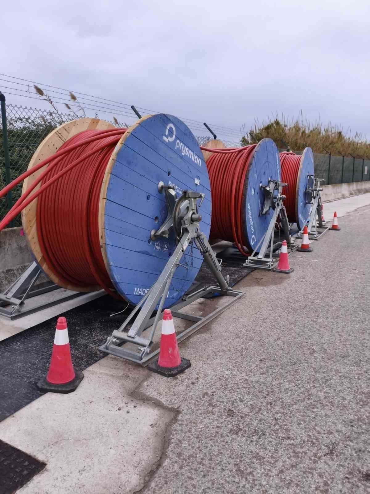 Liniero con equipo de seguridad trabajando en líneas eléctricas contra un cielo azul.