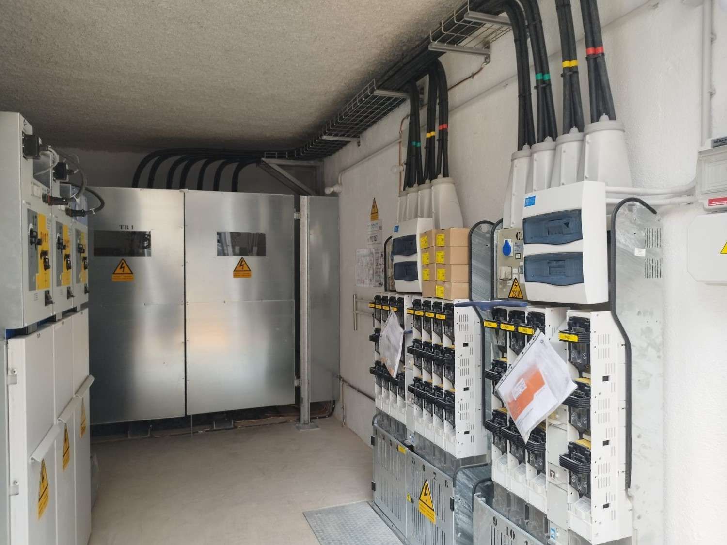 Paneles de control eléctrico en un pasillo industrial bien iluminado.