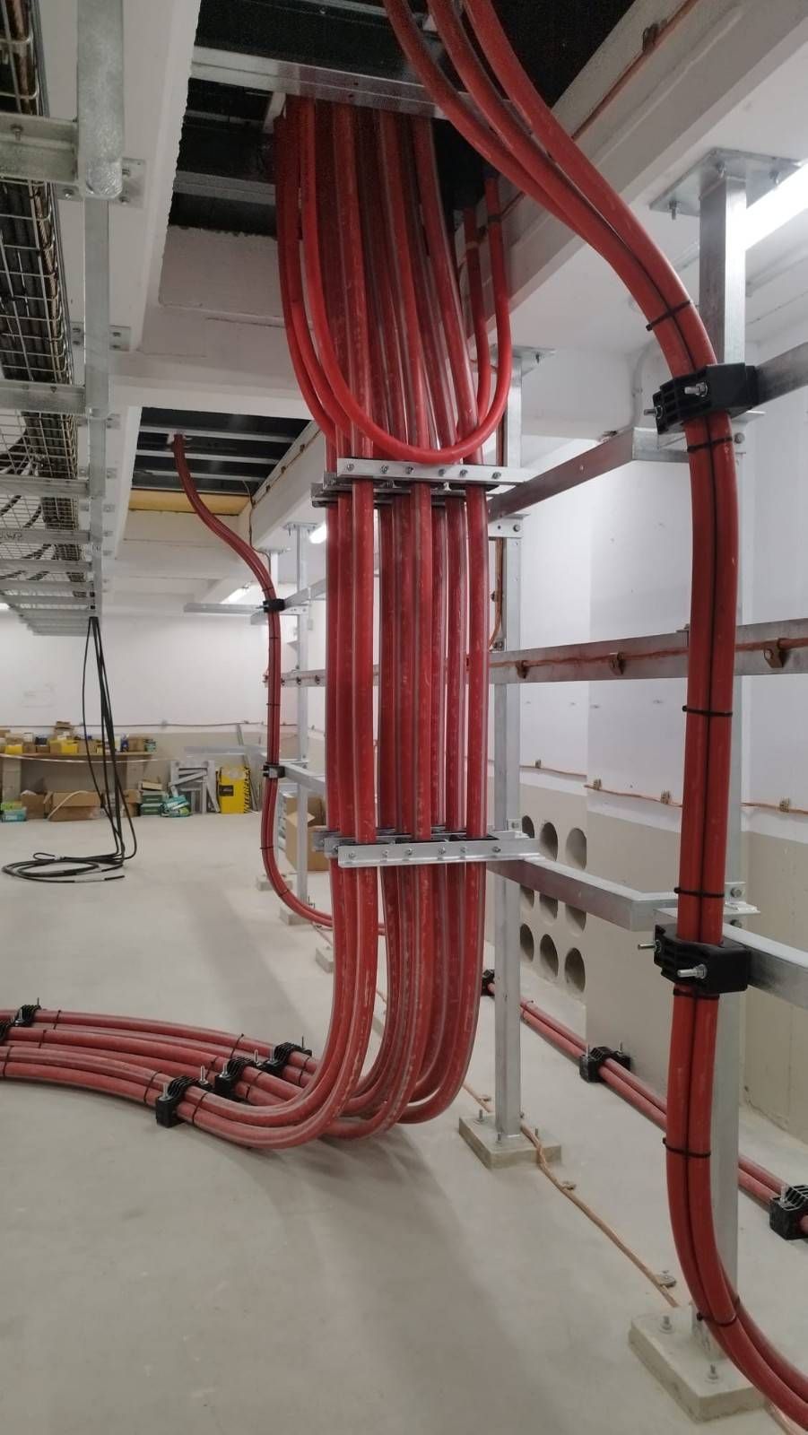 Dos trabajadores de servicios públicos con chalecos y cascos de color naranja trabajan en líneas eléctricas contra un cielo azul.