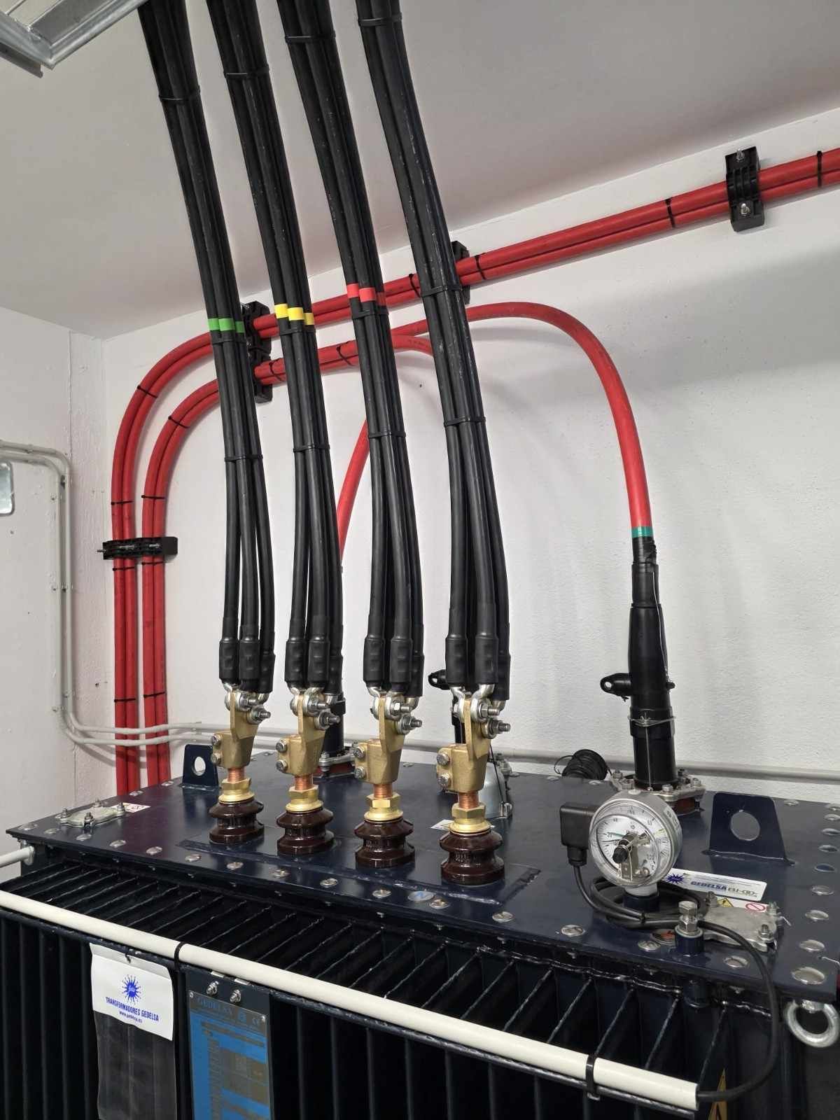 Tres aisladores eléctricos de alto voltaje con componentes rojos y amarillos.