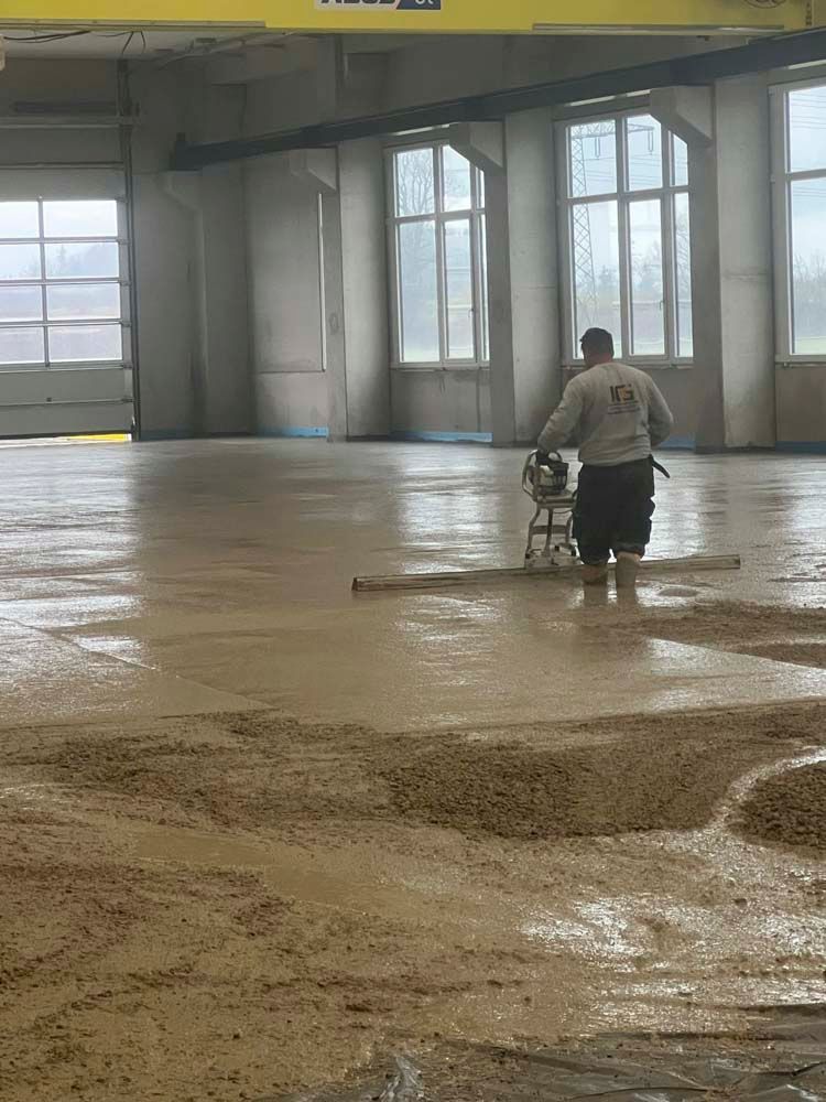 Ein Mann arbeitet an einem Betonboden in einem Gebäude.