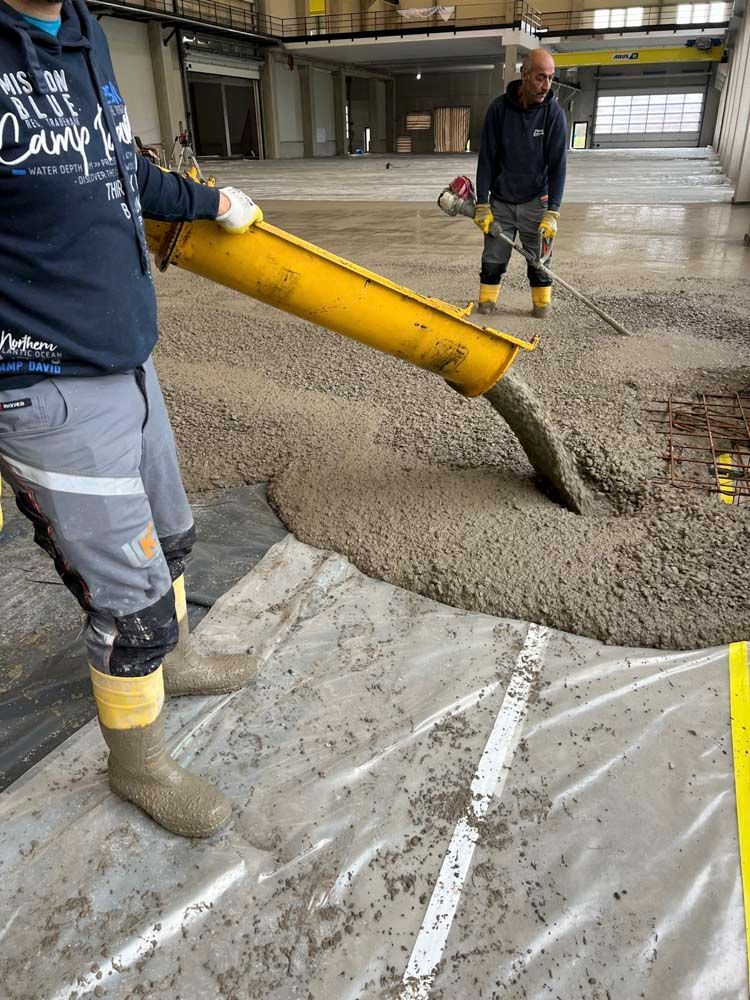 Ein Mann gießt Beton in ein Loch im Boden.