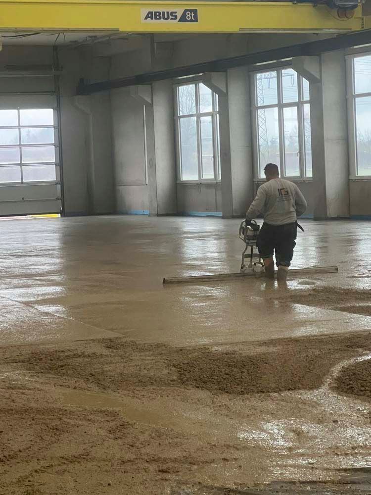 Ein Mann arbeitet an einem Betonboden in einem großen Gebäude.