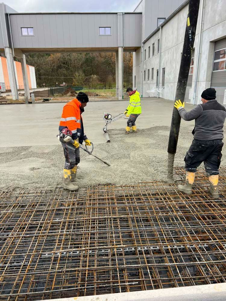 Eine Gruppe Bauarbeiter arbeitet an einem Betonboden.