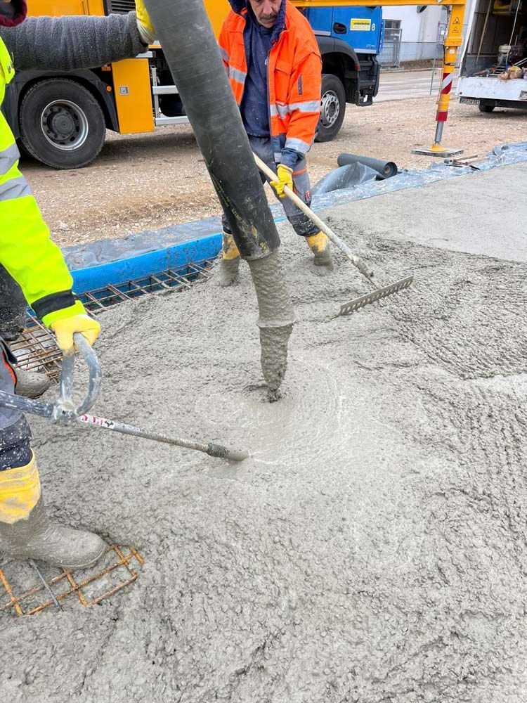 Eine Gruppe Bauarbeiter gießt Beton auf einer Baustelle.