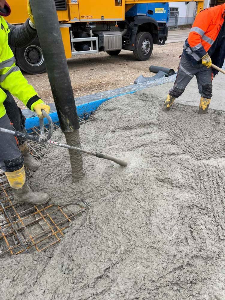Eine Gruppe Bauarbeiter gießt Beton auf einer Baustelle.