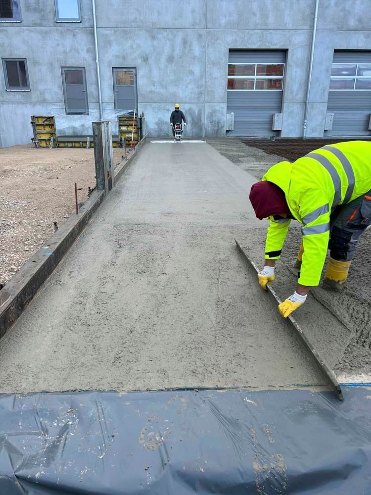 Ein Mann arbeitet an einer Betoneinfahrt vor einem Gebäude.