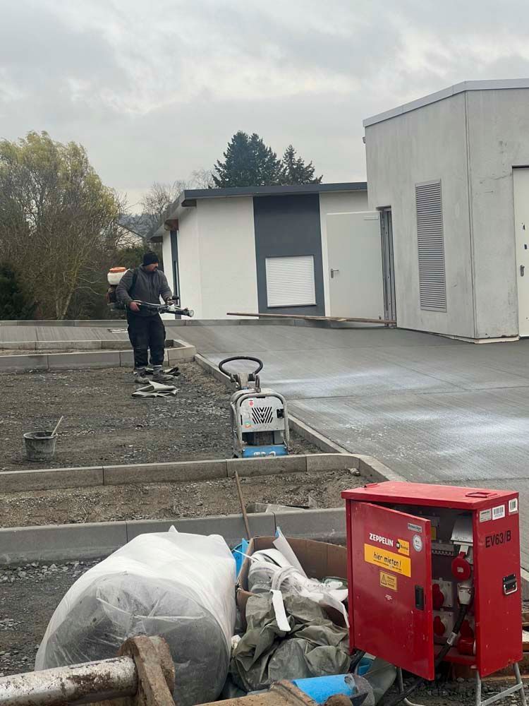 Ein Mann arbeitet an einer Betoneinfahrt vor einem Gebäude.