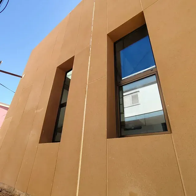 Dos ventanas en el costado de un edificio con un cielo azul de fondo.