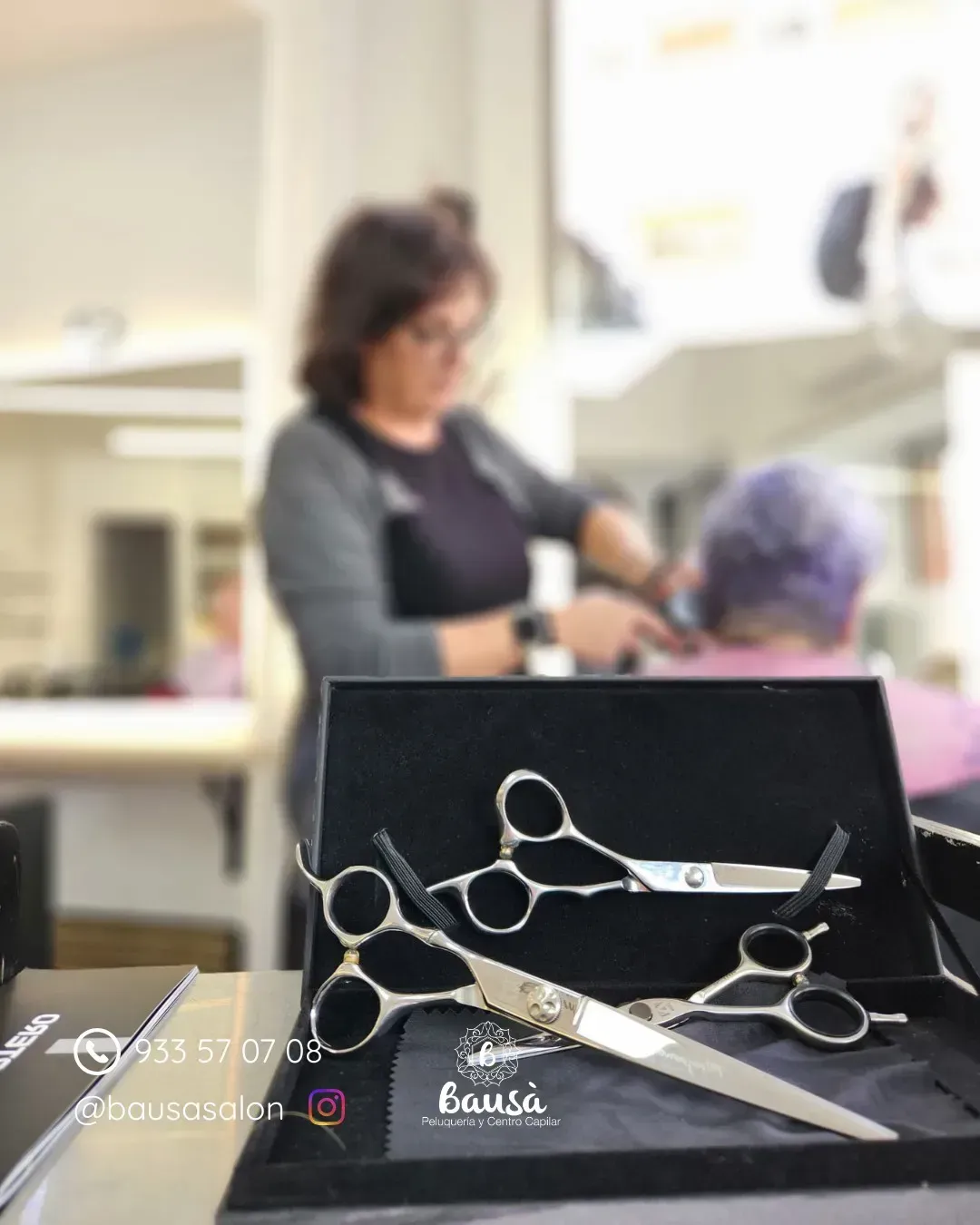 Unas tijeras de peluquería plateadas en un estuche forrado de terciopelo, con una estilista trabajando .