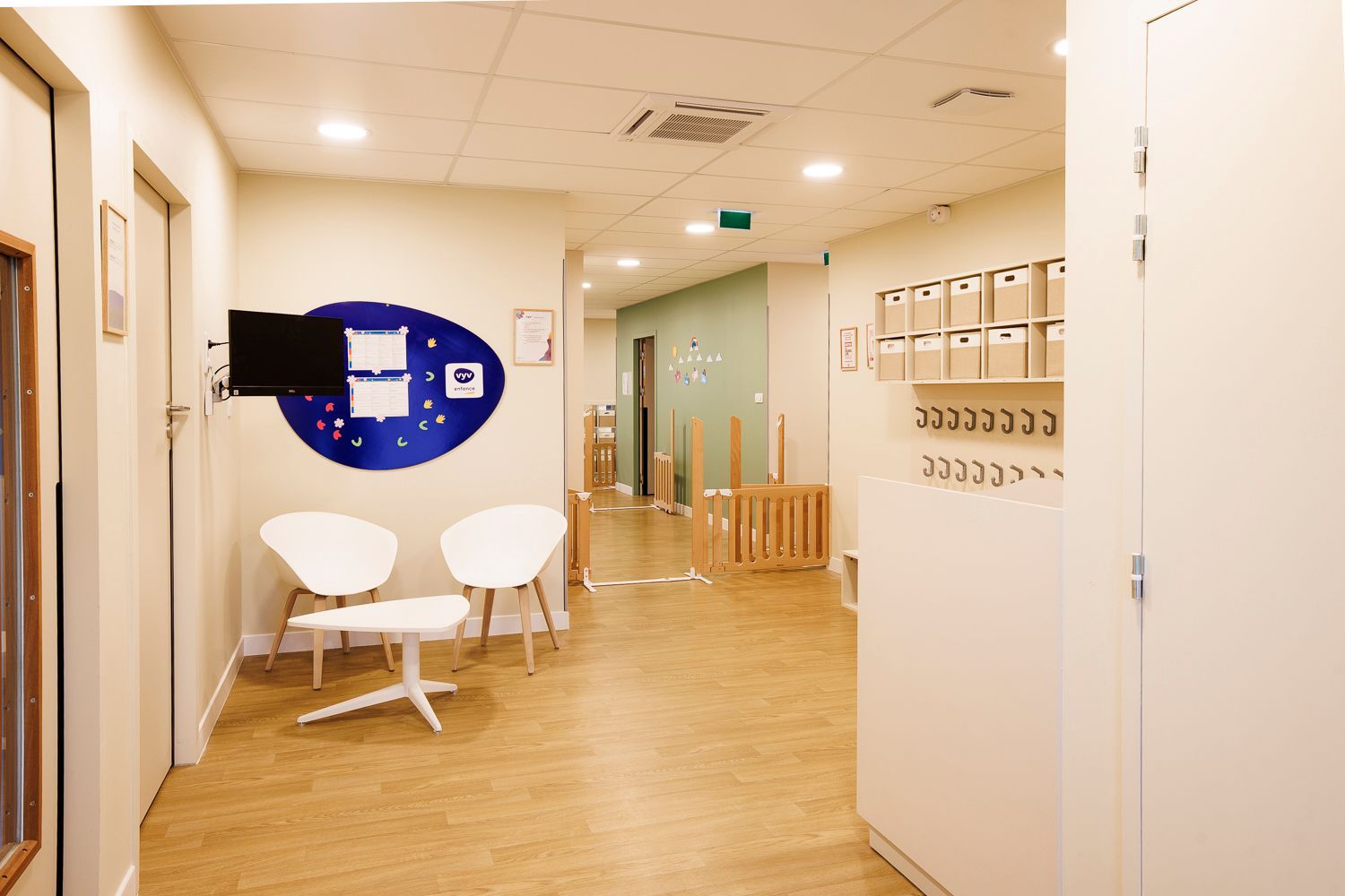 Entrée de la crèche avec deux chaises et une table dans un coin plus des porte-manteaux.