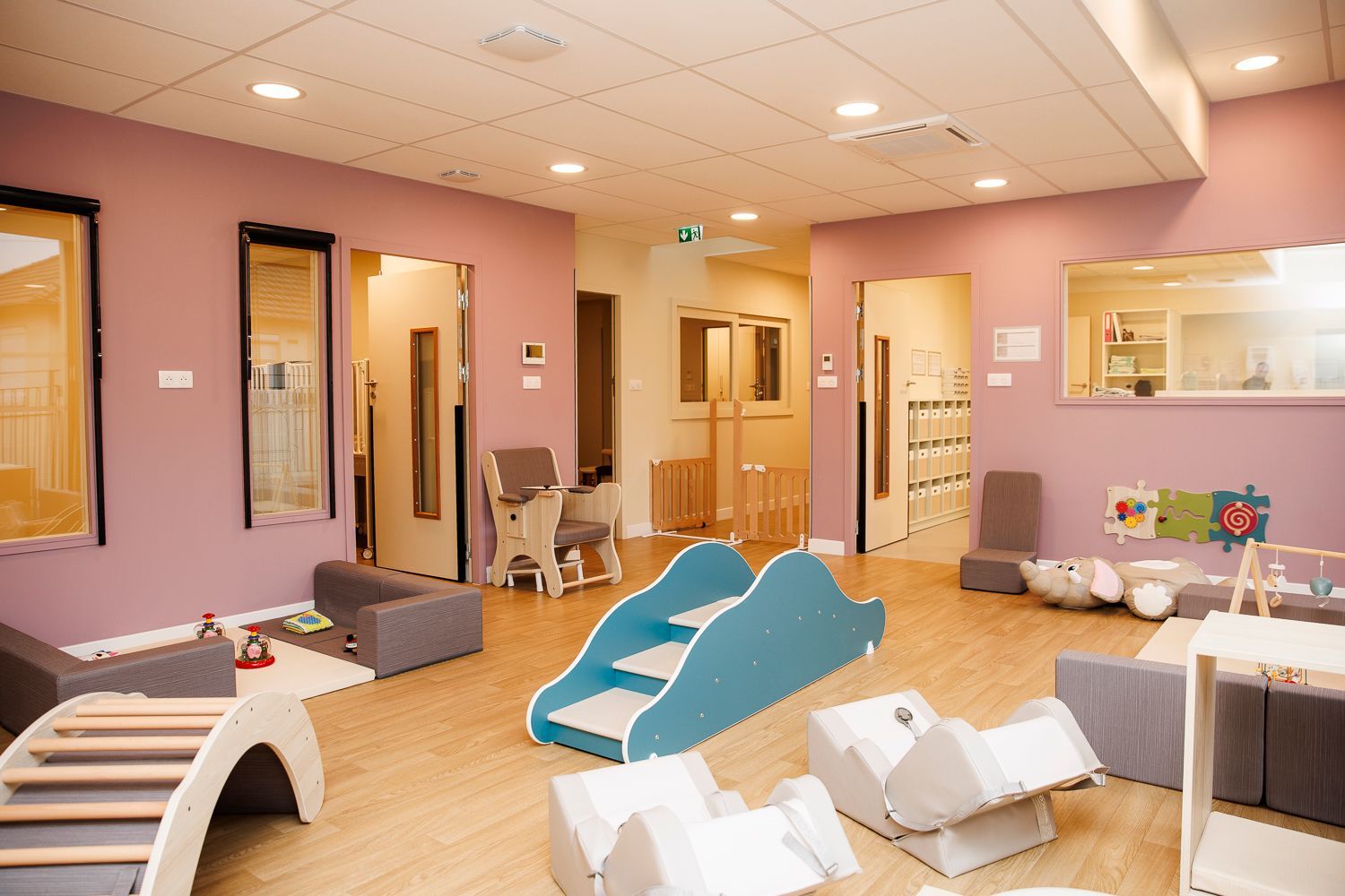 Pièce de motricité avec des jeux, un escalier pour l'apprentissage de la marche, petits transats pour un moment calme.