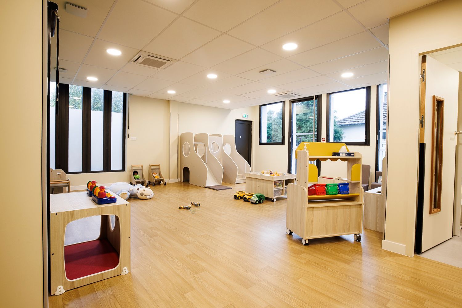 Pièce de la crèche avec des espaces de jeux et un coin de lecture.