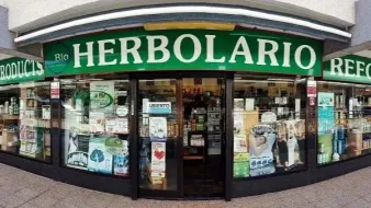La fachada de una tienda de alimentos naturales llamada Herbolario, con un letrero verde y escaparates.