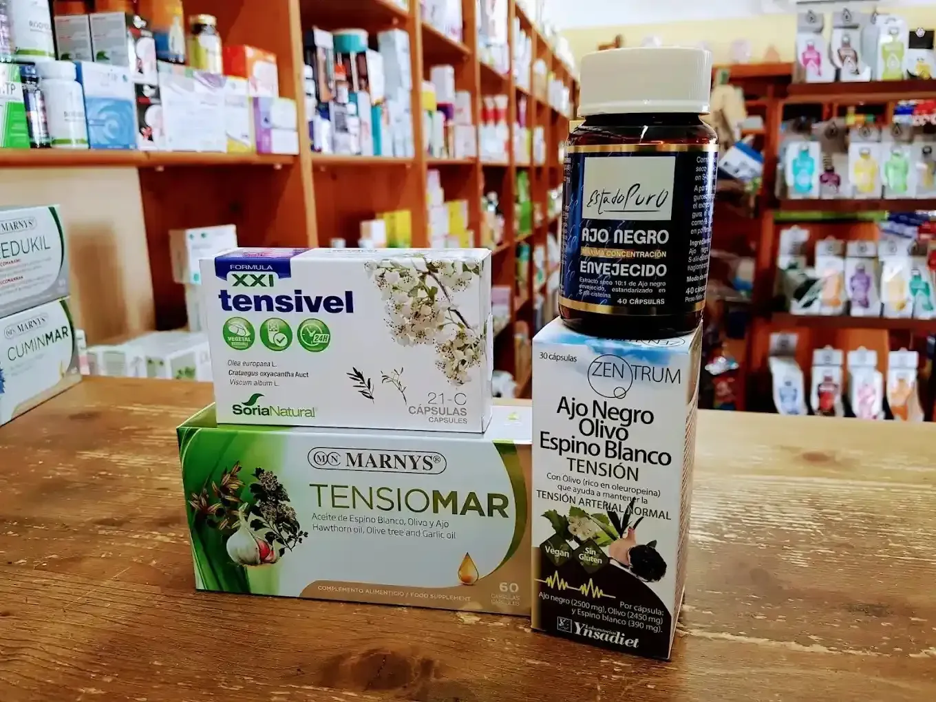 En una tienda, se exhiben tres productos complementarios para el control de la presión arterial en un estante de madera.