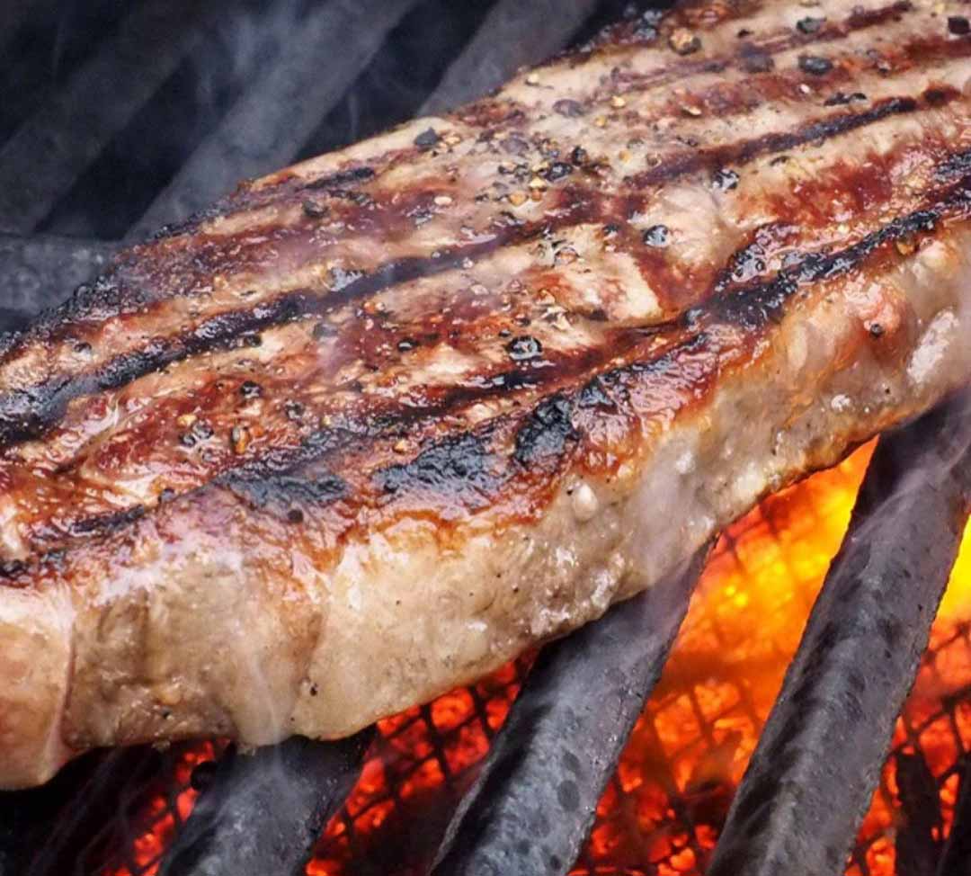 Un filete grande se cocina en una parrilla sobre el fuego.
