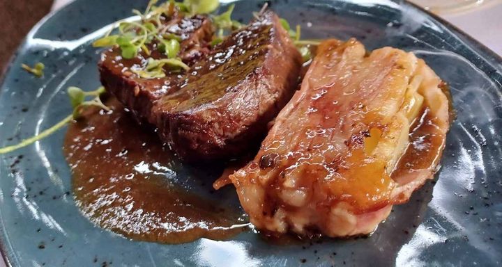 Un primer plano de un plato de comida con carne y tocino sobre una mesa.