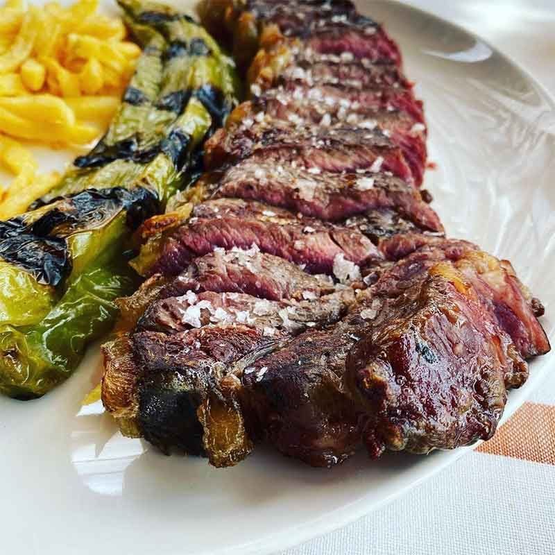 Un plato blanco cubierto con un filete y papas fritas.
