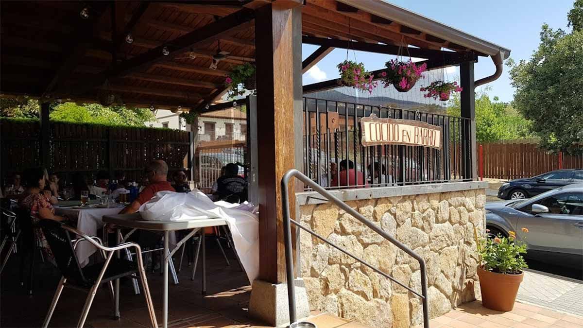Un grupo de personas están sentadas en mesas afuera de un restaurante.